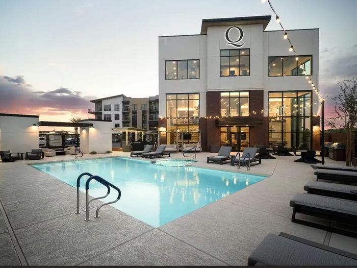 The clubhouse and pool deck at Quintana at Cooley Station at dusk, with the four-storey apartment building behind