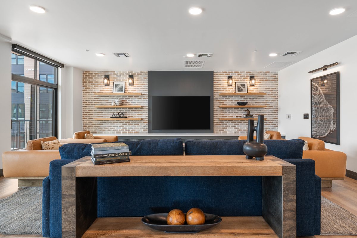 Resident lounge with brick wall and navy sofas at Quintana at Cooley Station, Gilbert