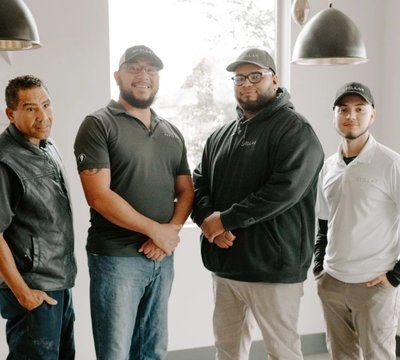 Four Stellar maintenance technicians in branded caps and polos at a community office