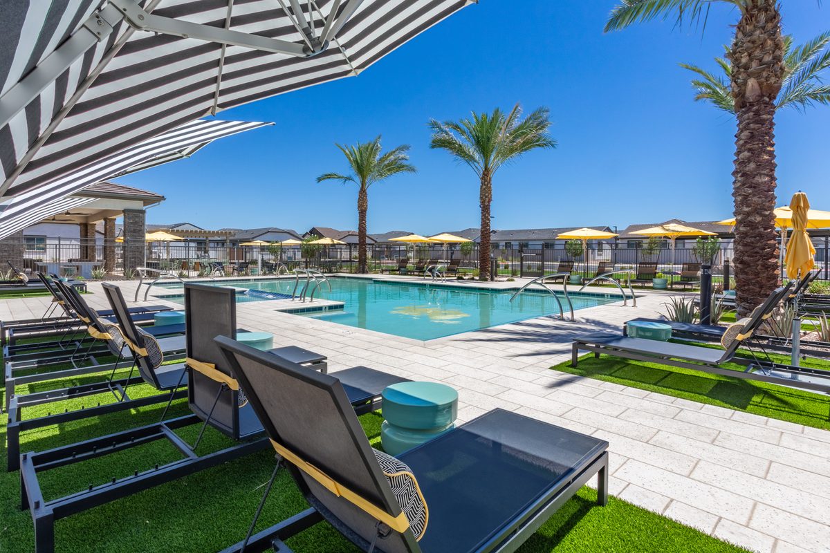 Pool deck with striped and yellow umbrellas at a Stellar build-to-rent Village community